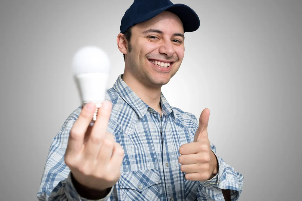 a smiling electrician holding an LED bulb