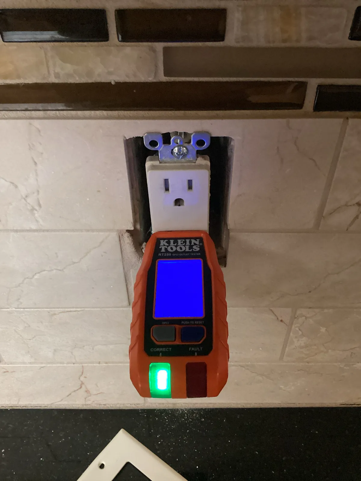 Tester confirming a new GFCI outlet in a kitchen backsplash, Northern Colorado